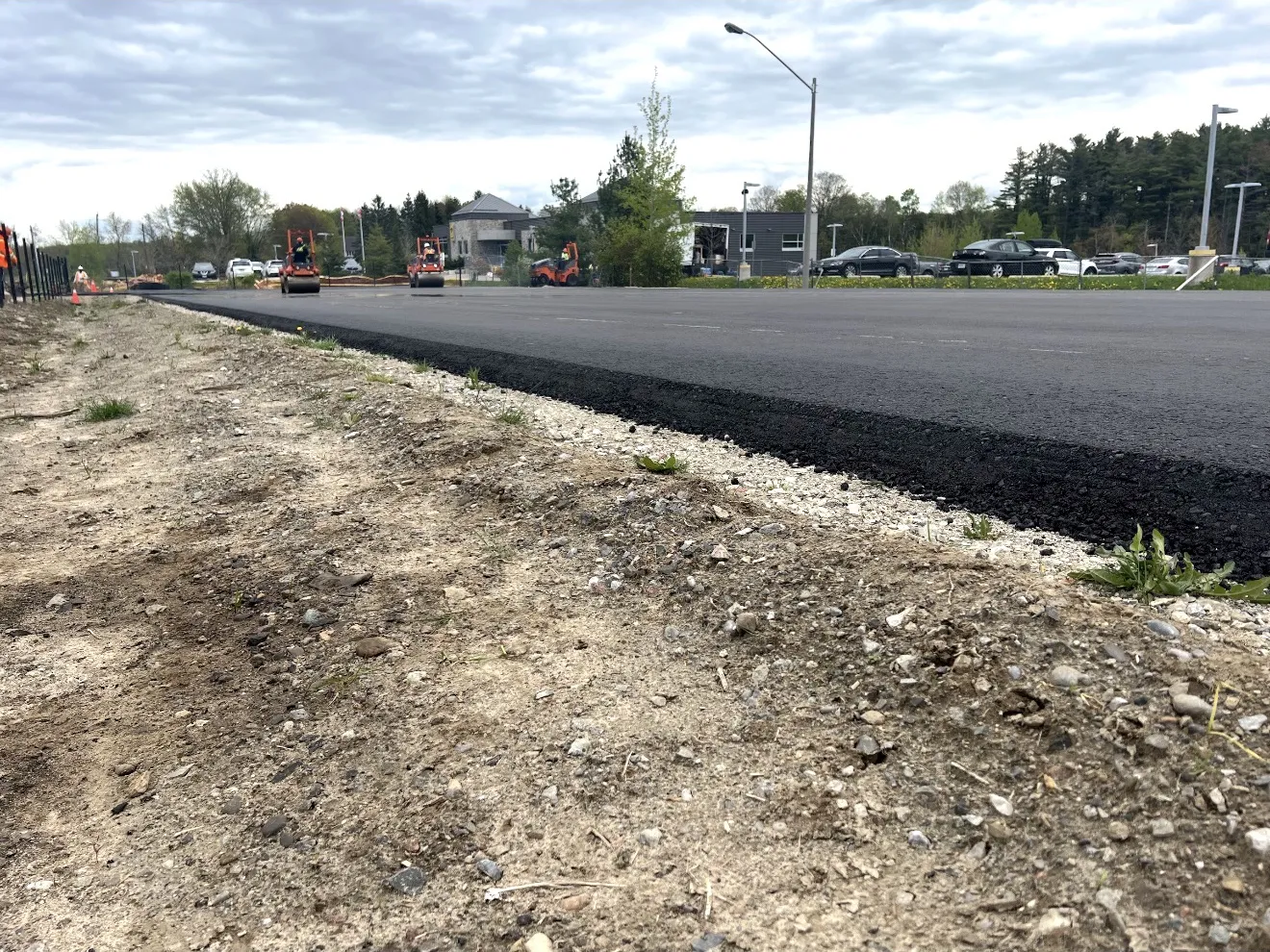 Fresh asphalt pavement with construction equipment working in the background